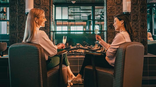 Two women drinking champagne by the bar