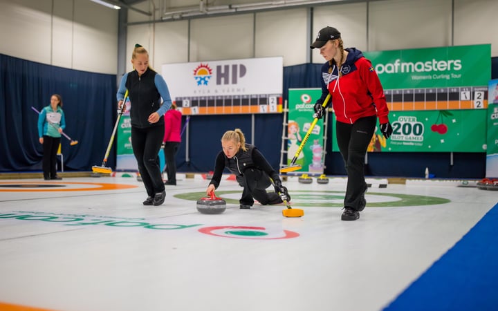 Tre flickor som spelar curling