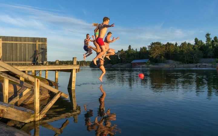 Ungdomar hoppar från bryggan i vattnet